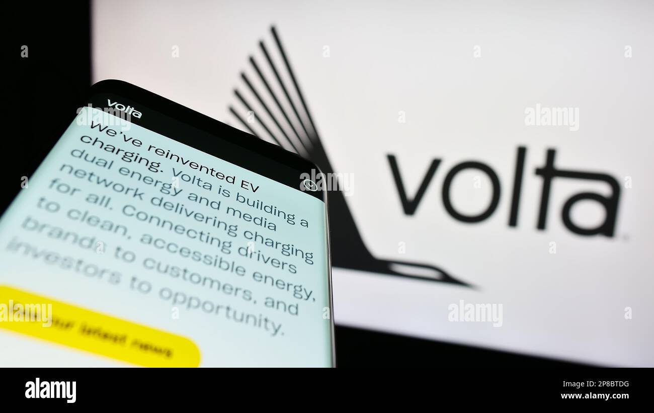 Mobile phone with website of American EV infrastructure company Volta Charging LLC on screen in front of logo. Focus on top-left of phone display. Stock Photo