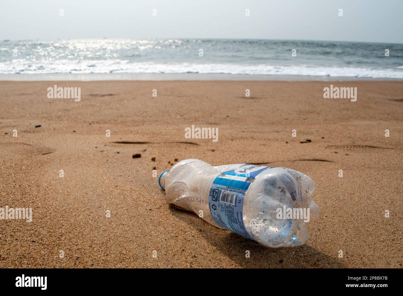 Candolim, Goa, India - January 2023: A plastic water bottle lying on the sand at a tourist beach in Sinquerim. Stock Photo