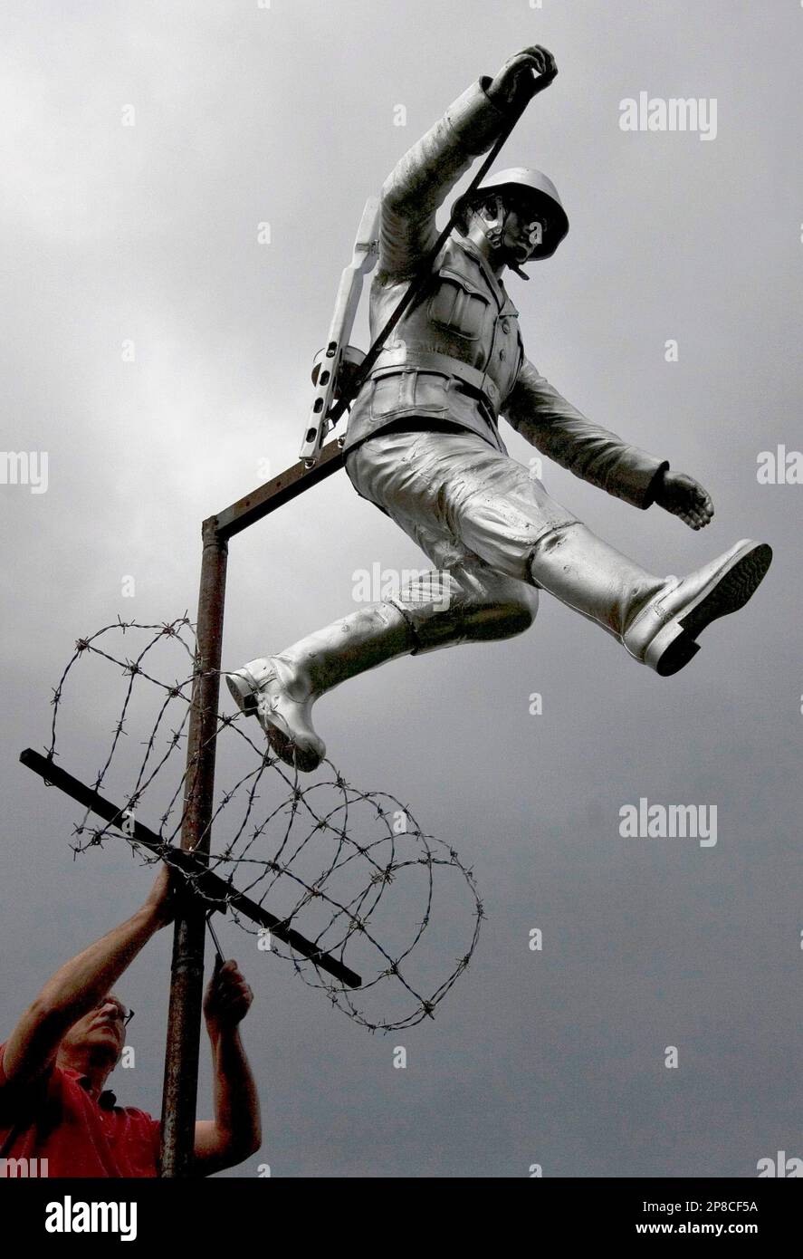 A worker, seen, placing the sculpture of East German border guard