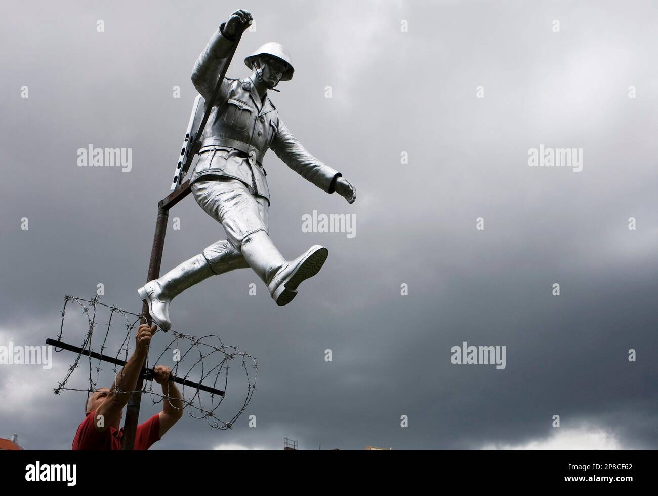 A worker, seen, placing the sculpture of East German border guard