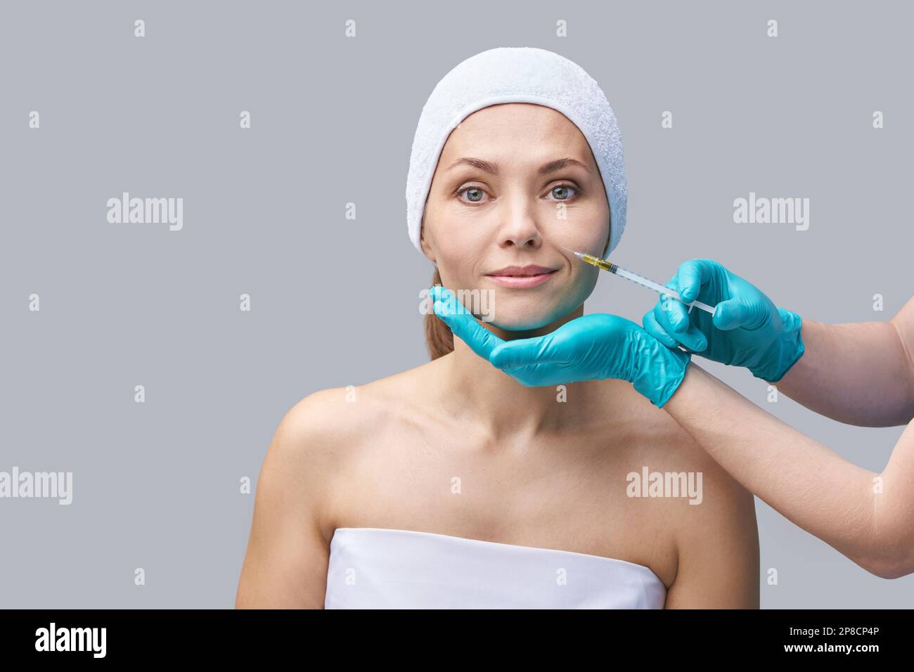 Face needle injection. Young woman cosmetology procedure. Doctor hand in green glove. Pretty female patient. Forehead spa salon. Beauty treatment. Healthy skin. Plasmolifting rejuvenation. Dermatology Stock Photo