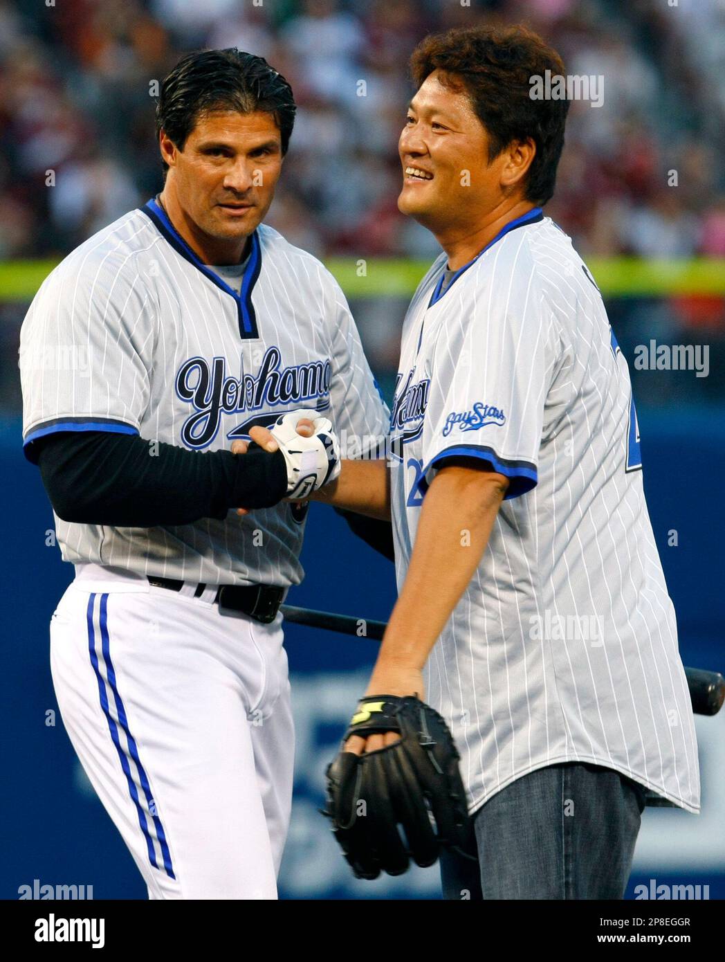 Former major league MVP player Jose Canseco, left, and former Seattle Mariners closer Kazuhiro Sasaki, both wearing Yokohama BayStars jerseys, react after attending the first-pitch ceremony for a Japanese professional baseball game