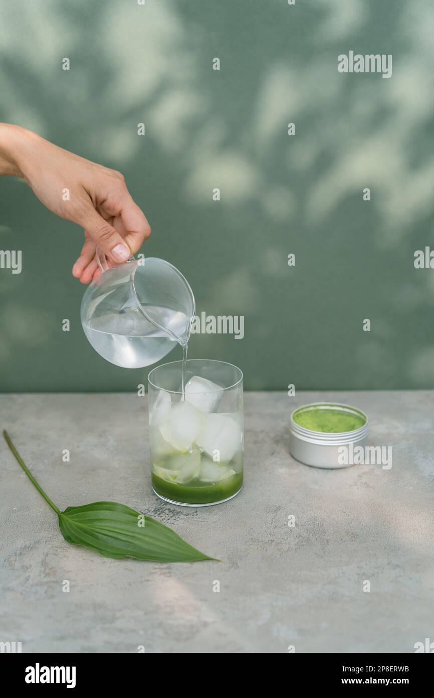 Closeup of a woman pouring water into a glass to make an iced matcha drink Stock Photo Alamy