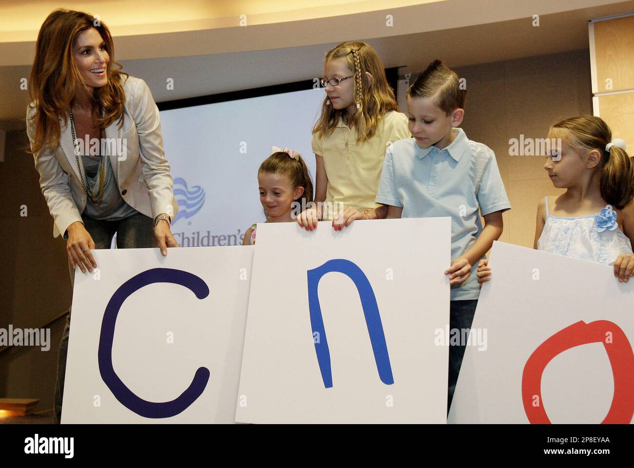 Cindy Crawford, left, helps spell out Cardon with former patients, left