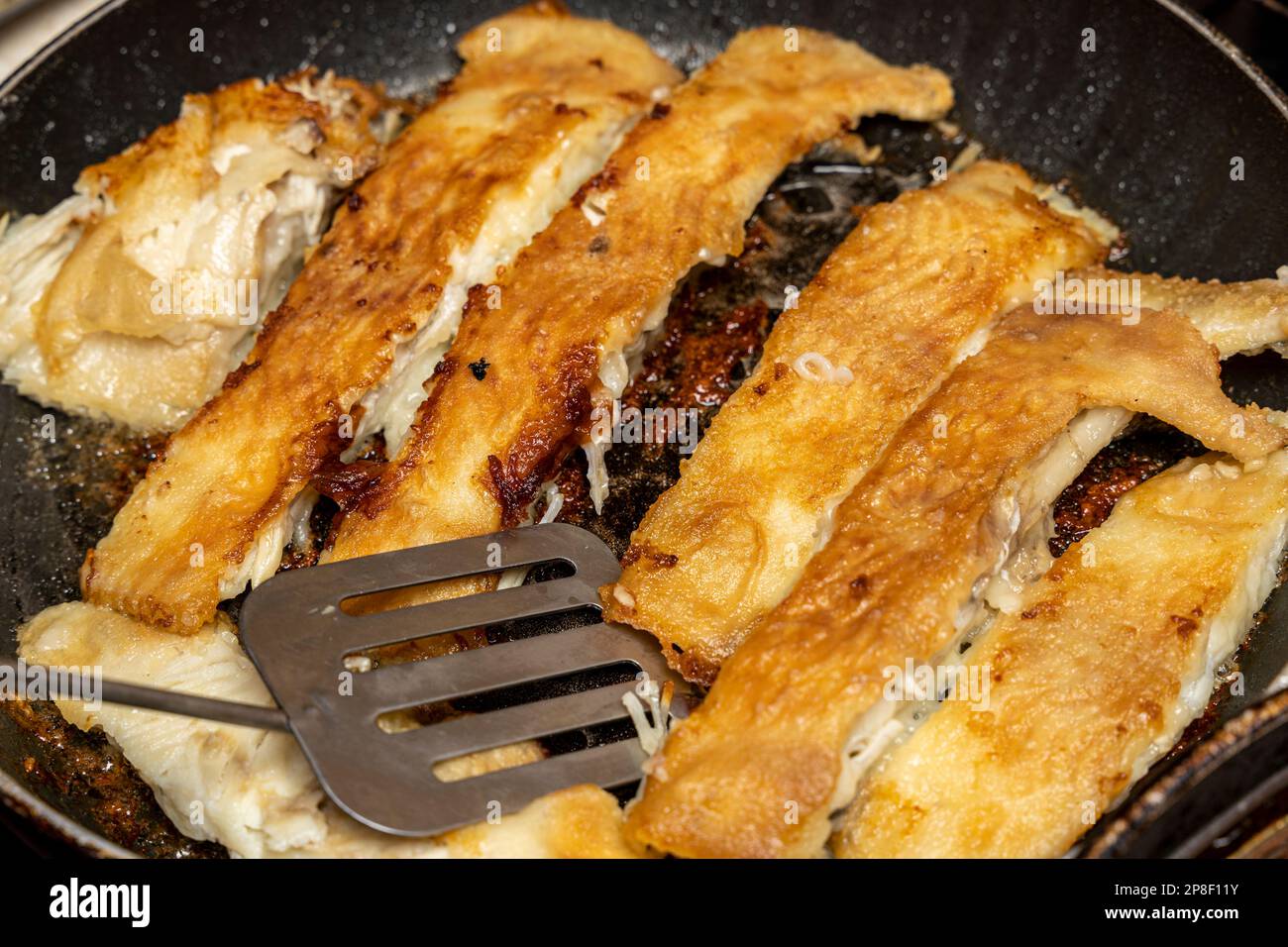 the cook checks the readiness of the fish with a fork Stock Photo - Alamy