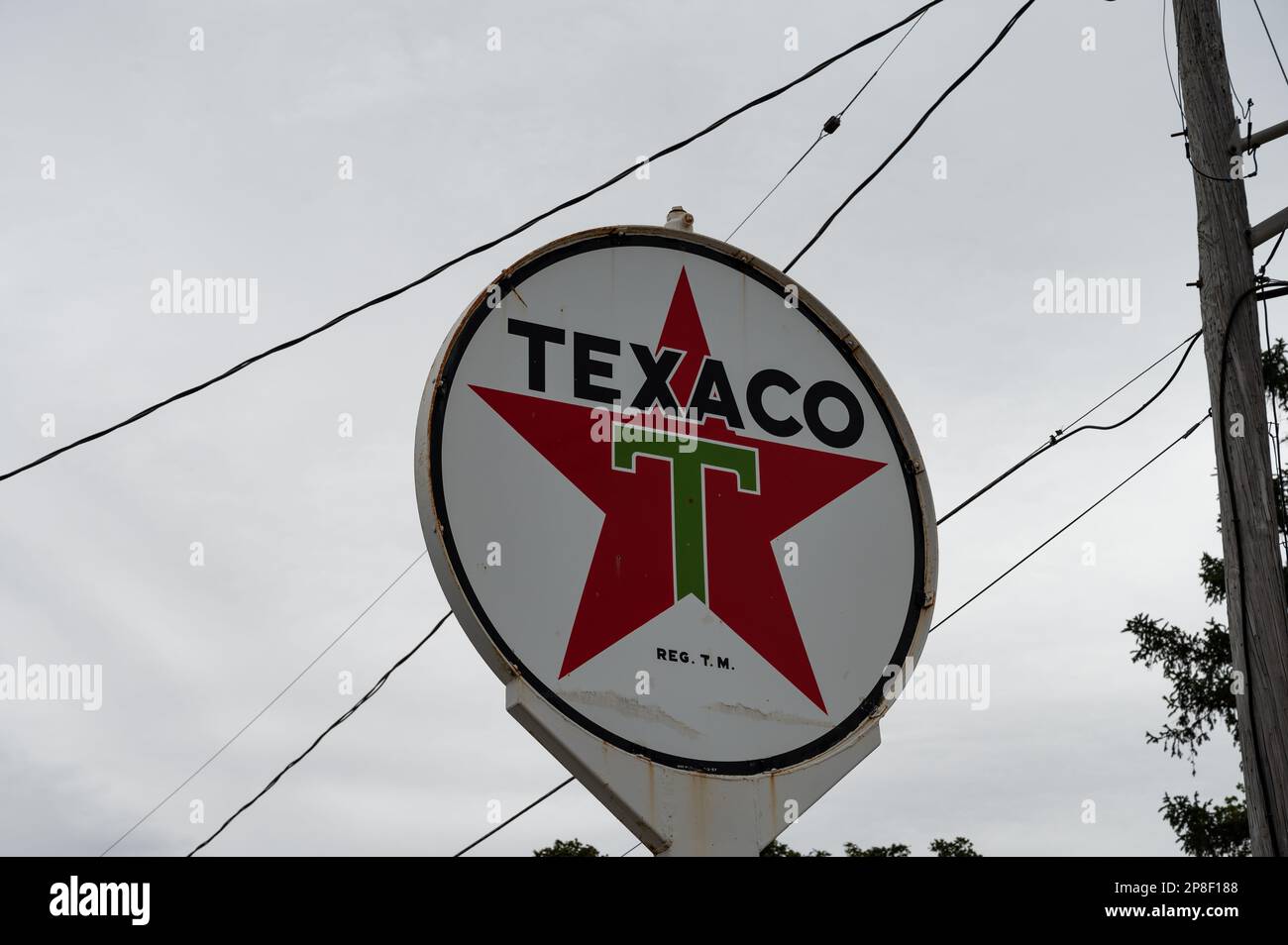 Texaco Sign Posts A white Texaco sign hangs on a pole in front of a telephone pole on a ...