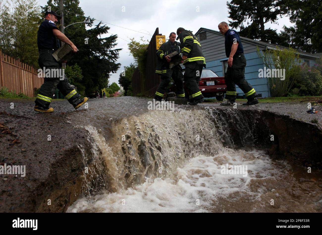 Firefighters use bricks and rocks to divert water from homes after a 12