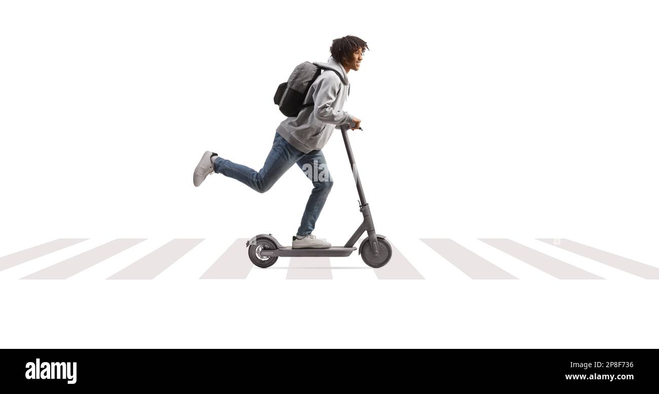 Full length profile shot of an african american male student riding an electirc scooter on e pedestrian crossing isolated on white background Stock Photo