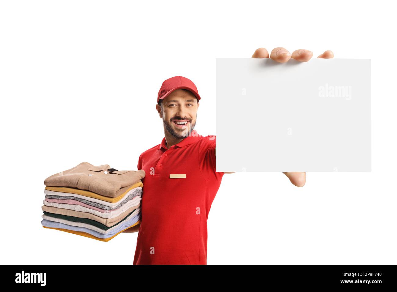 Laundry worker holding a pile of folded clothes and showing a blank card isolated on a white background Stock Photo