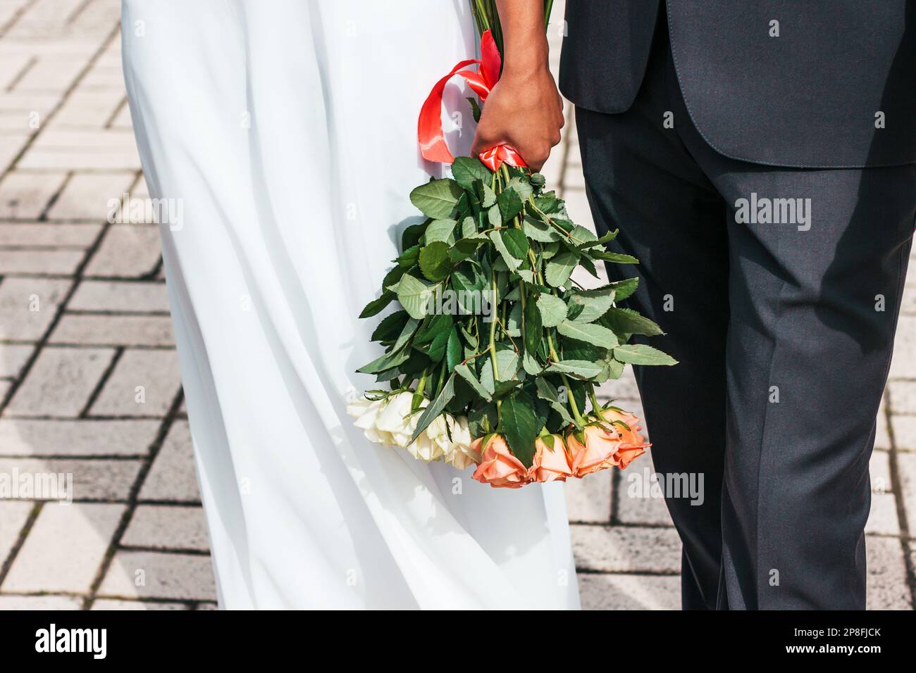 Bridal bouquet, a beautiful arrangement of flowers that complements the bride's outfit. Soft colors. Bride and groom in a magical moment. Stock Photo