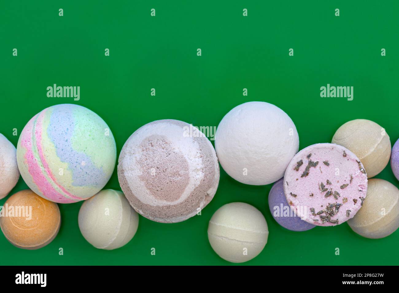Multicolored bath bombs on a green background, top view. Stock Photo