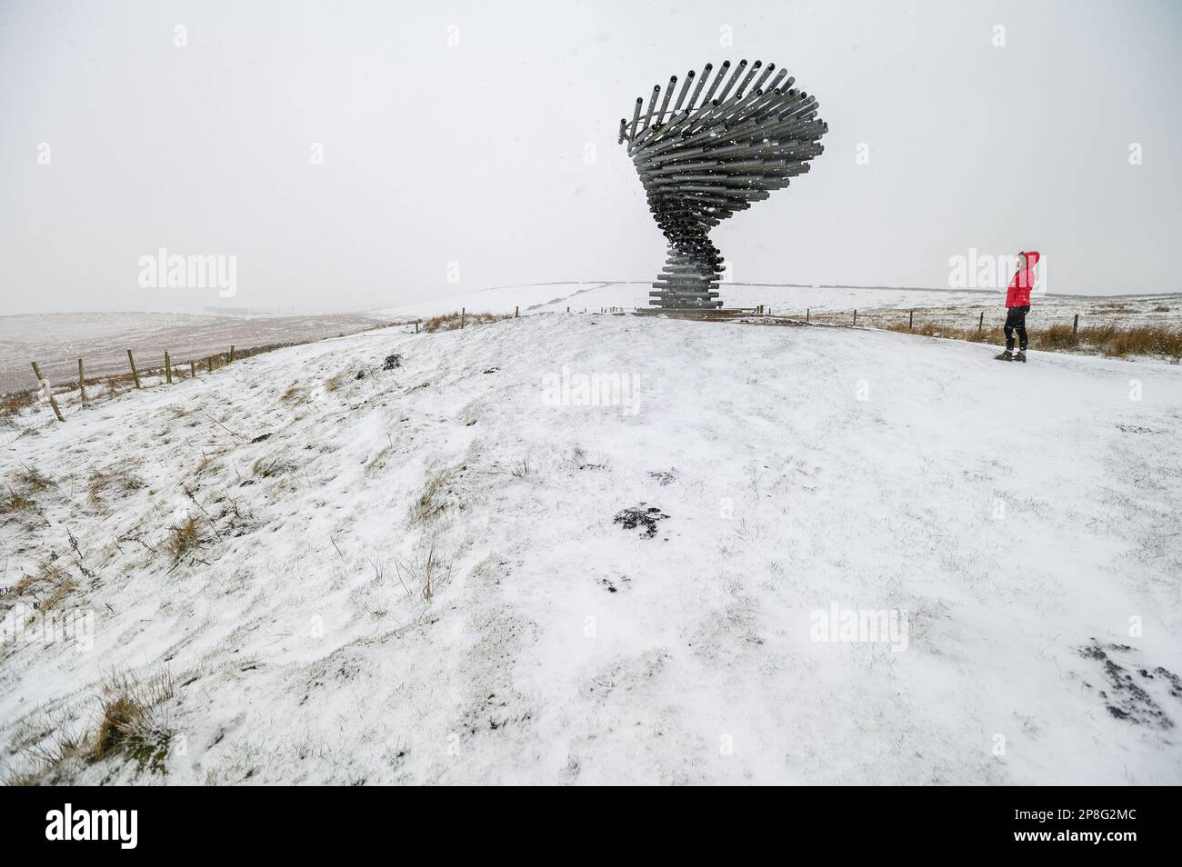 Burnley, Lancashire, UK, Thursday March 09, 2023. A woman braves the blizzard like conditions above the town of Burnley as she walks towards the Singing Ringing Tree Panopticon on Crown Point. The north of England is under a Met Office Amber Warning for snow and ice for the next 24 hours. Credit: Paul Heyes/Alamy News Live Stock Photo