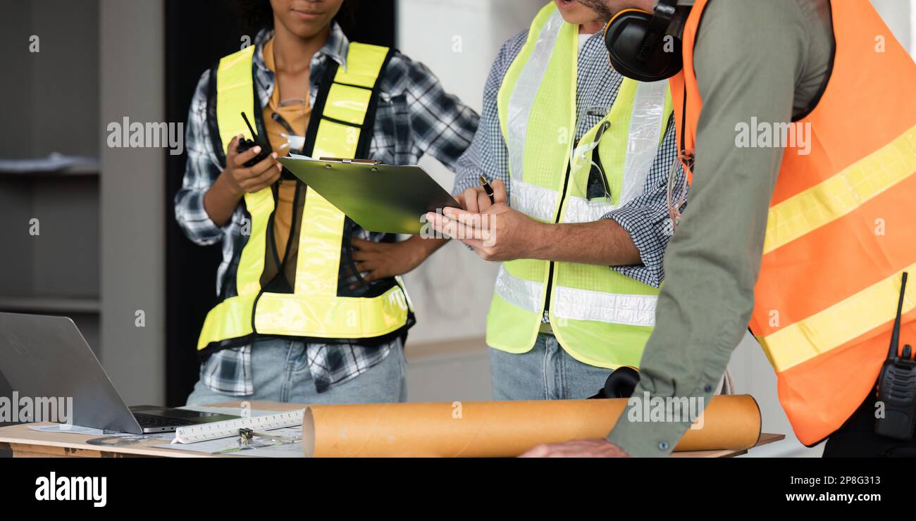 Architect team working with blueprints for architectural plan, engineer sketching a construction project on table in working site Stock Photo