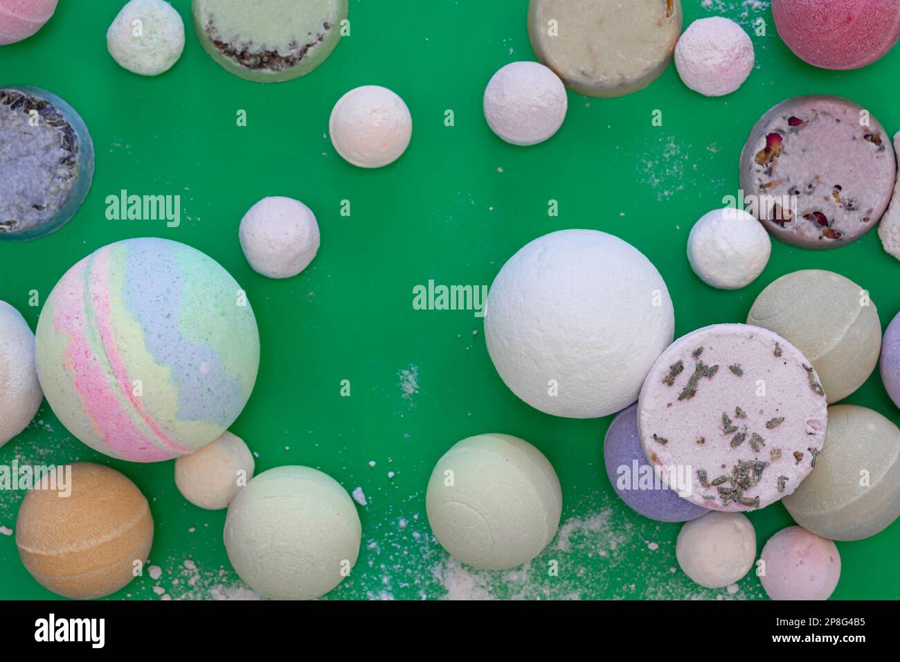 Multicolored bath bombs on a green background, top view. Stock Photo