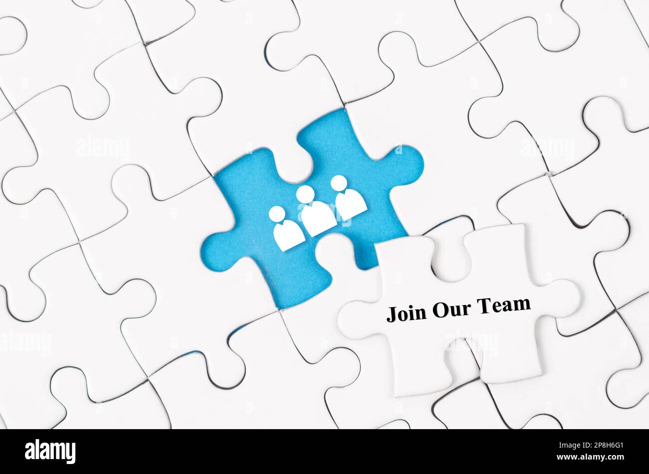 Join our team concept. White jigsaw puzzle with word and blue background Stock Photo
