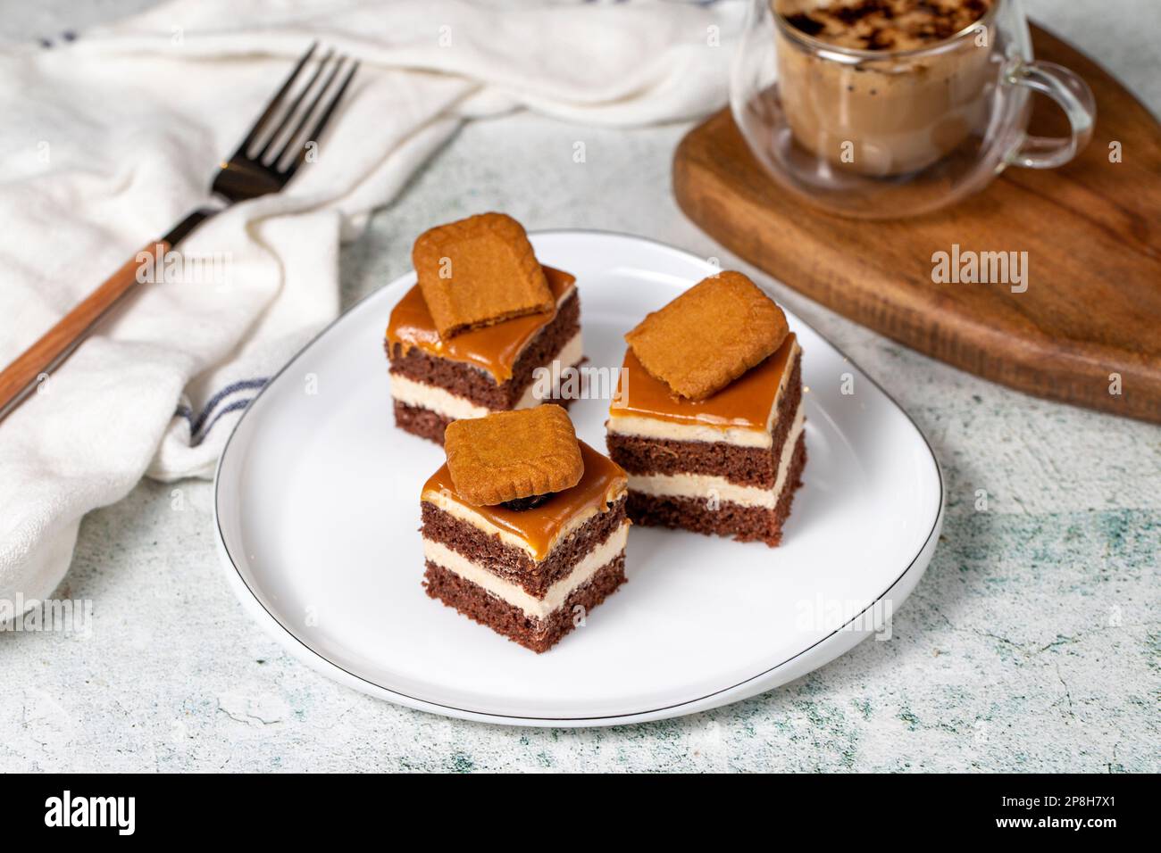 Small dessert cakes. Caramel petit four on a white plates in dark background. Biscuit french petit four cake Stock Photo