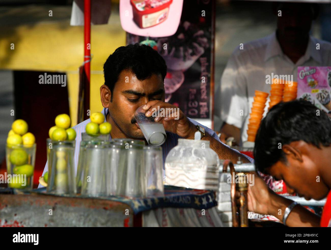 A person quenches his thirst by drinking lime water from a road-side  vendor, in New Delhi, India, Friday, May 1, 2009. A scorching heat wave has  swept through several Indian states leading