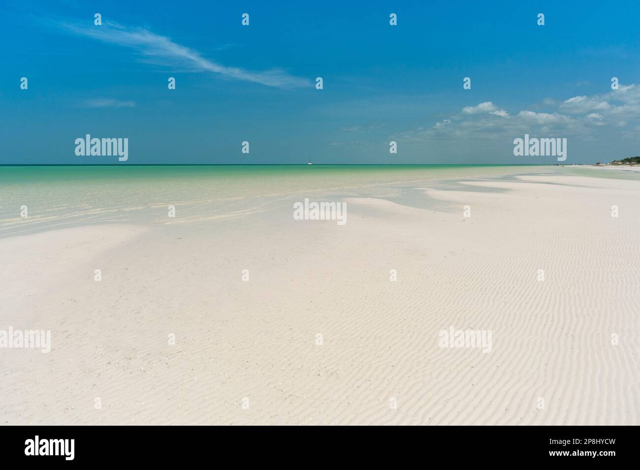A panoramic view of a deserted white sand tropical beach with a blue sky, perfect for relaxing and rejuvenating. Stock Photo