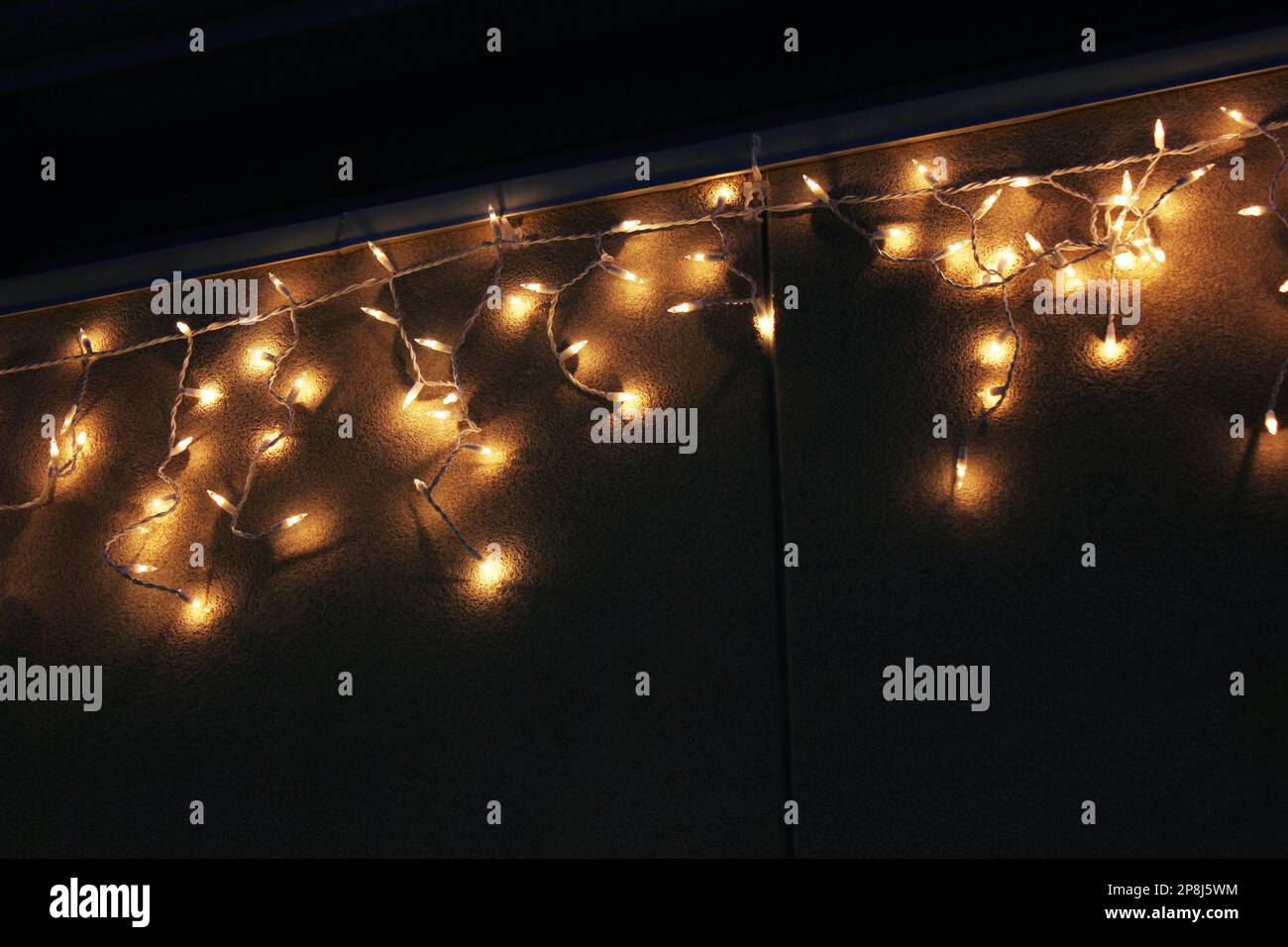 Christmas lights glow against exterior house wall Stock Photo - Alamy