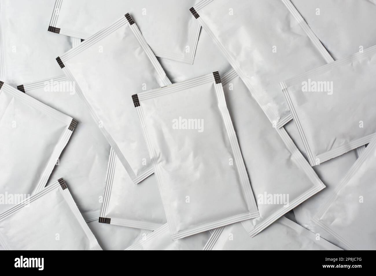 pile of blank white sachet packets full frame background, close-up of scattered food or medicine drug packaging mockup template Stock Photo