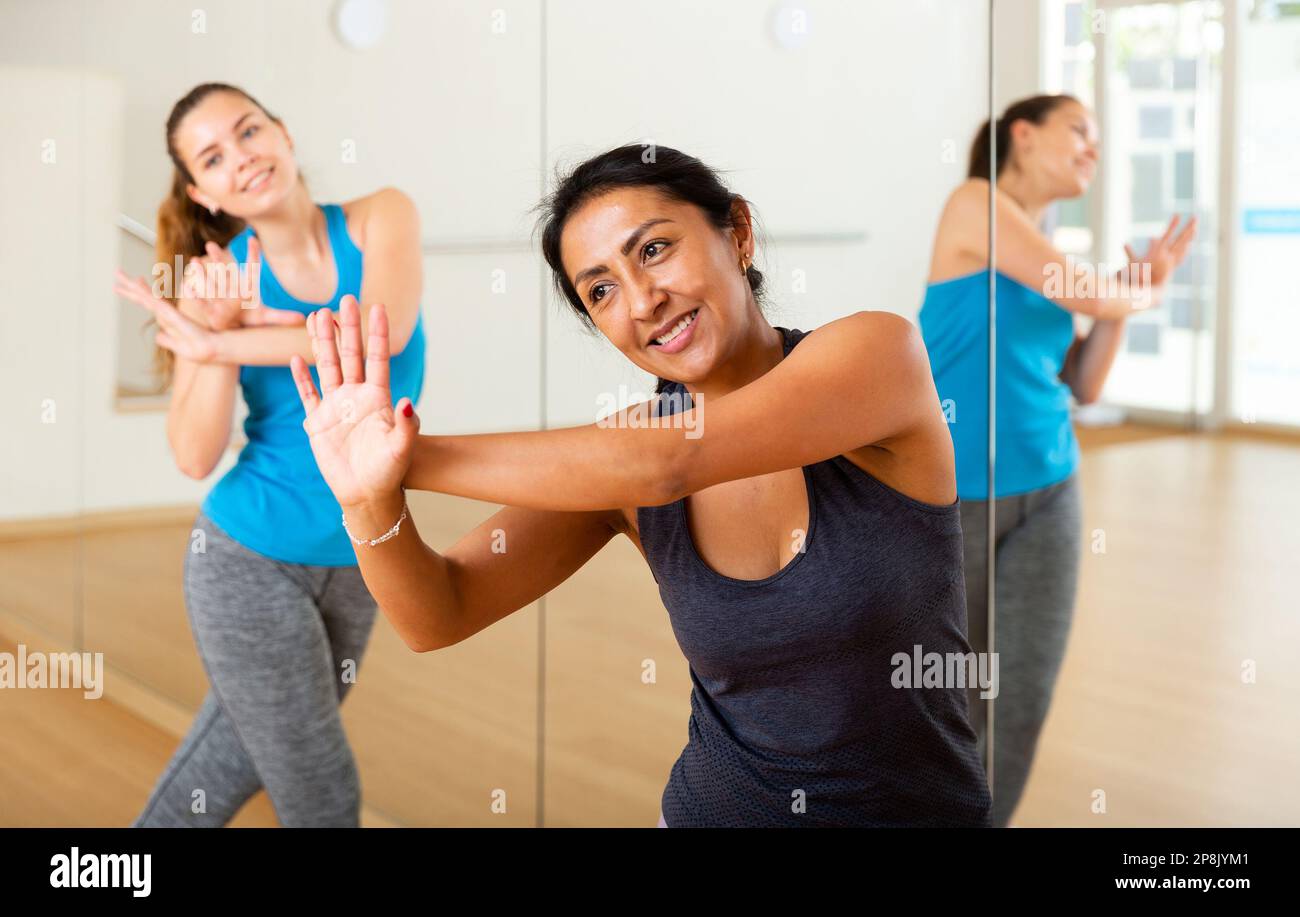 Cheerful hispanic woman practicing vigorous dance in group class Stock Photo