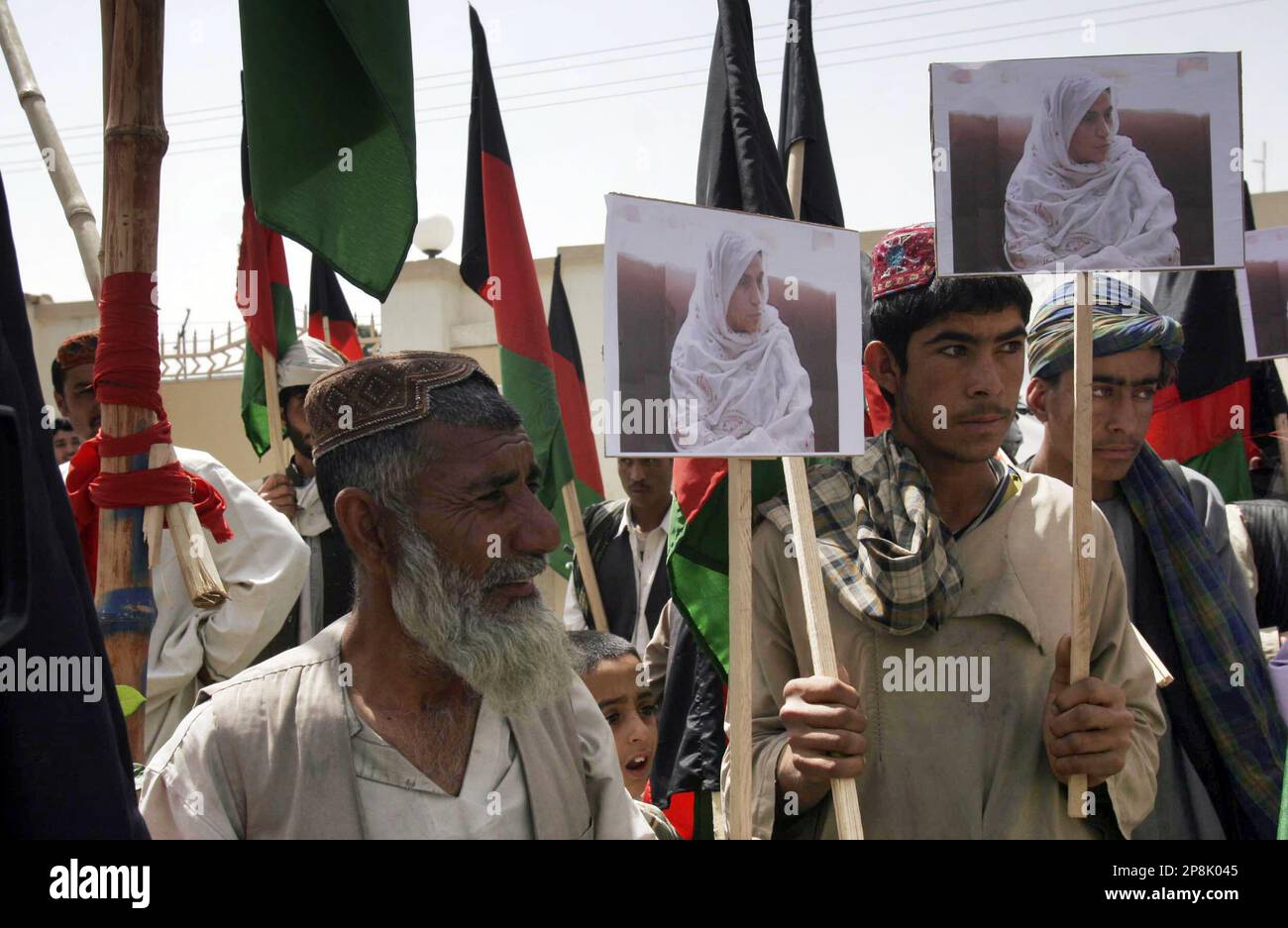 Afghan demonstrators hold pictures of late Sitara Achakzai during a