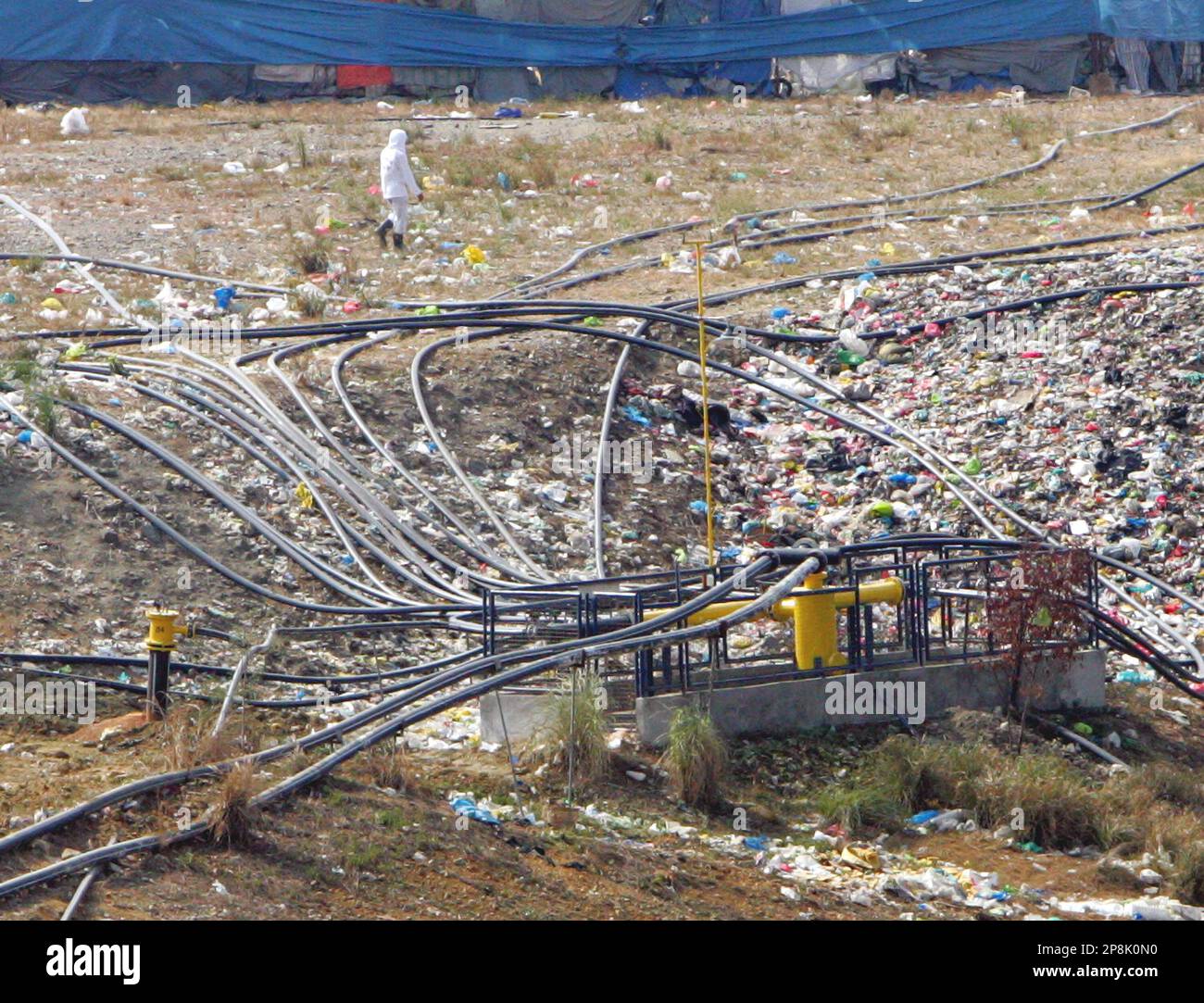 A worker walks past rubber tubes used in collecting methane gas at the
