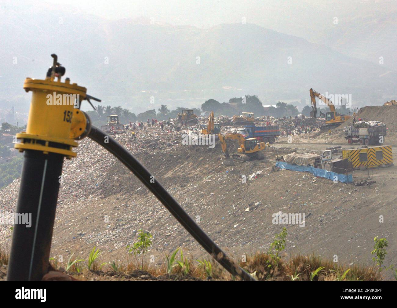 A vent that collects methane gas protrudes on the ground as people and