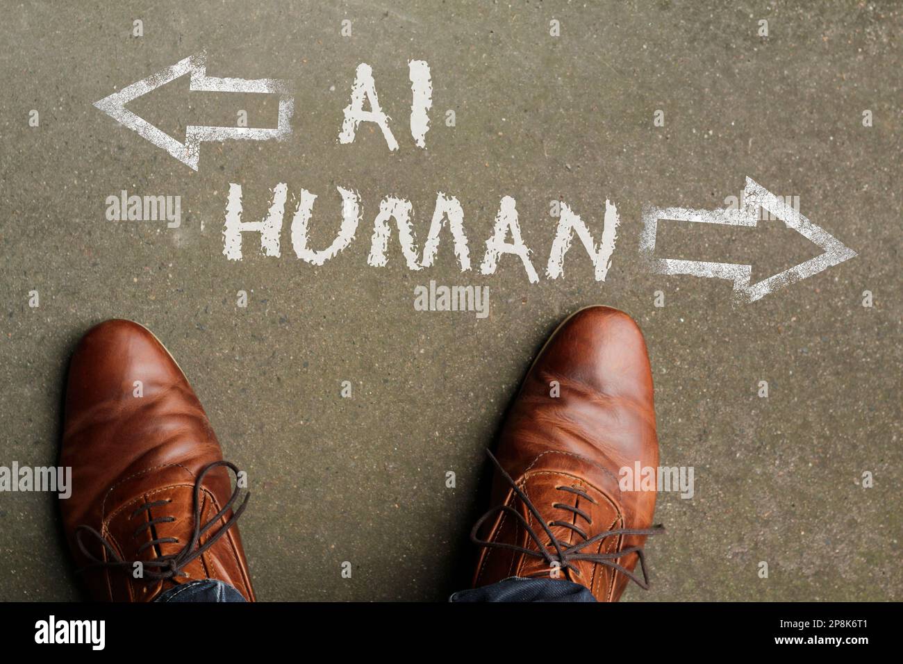Man looking down at the words Artificial Intelligence - AI - and Human chalked onto the floor Stock Photo