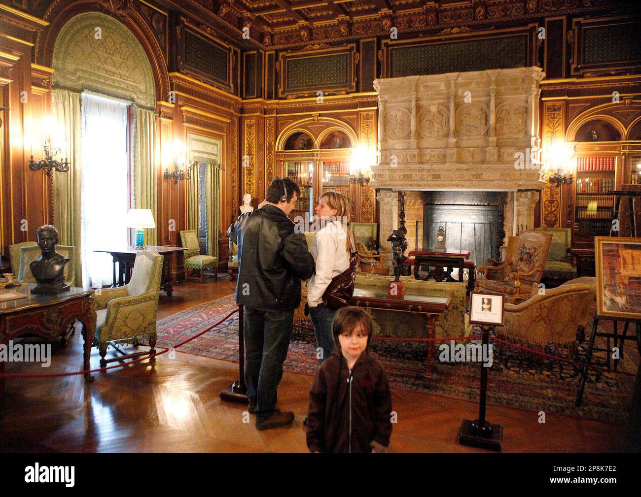 Steve Vigneault and Nadia Bockhard, rear, and their son David Vigneault view the library Monday, April 6, 2009, during an audio-guided tour of The Breakers, a legendary 70-room summer estate built by former Railroad magnate Cornelius Vanderbilt II, in Newport, R.I. The new audio tour is intended to make the city's most glamorous and popular Gilded Age mansion more historically accurate and relevant. (AP Photo/Stephan Savoia) Stock Photo