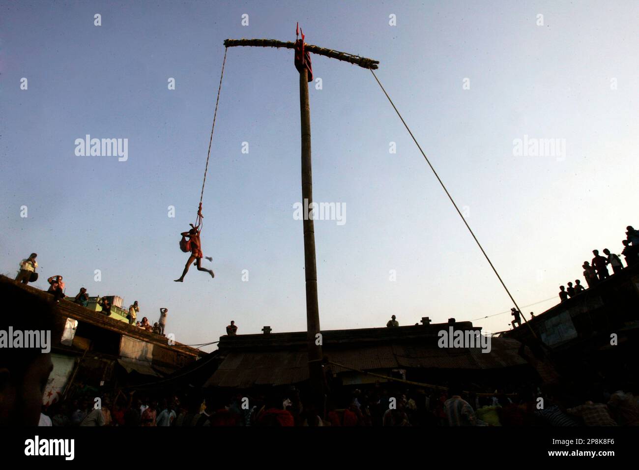 A Hindu devotee tied with rope swings on a pole as he performs a ritual