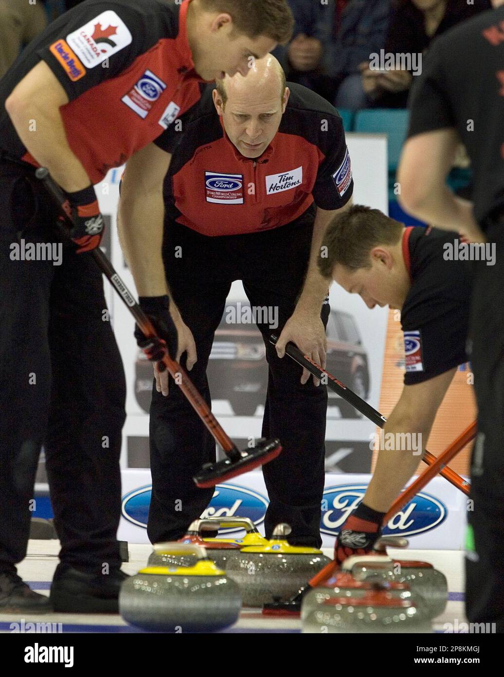 Team Canada's John Morris, left, and Ben Hebert, sweep as Kevin Martin