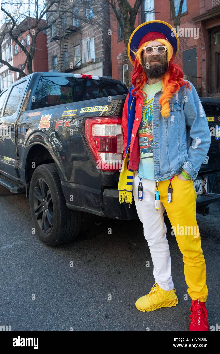 A middle aged orthodox Jewish man celebrates Purim wearing colorful clothes, shoes & wig. In Williamsburg, Brooklyn, New York. Stock Photo