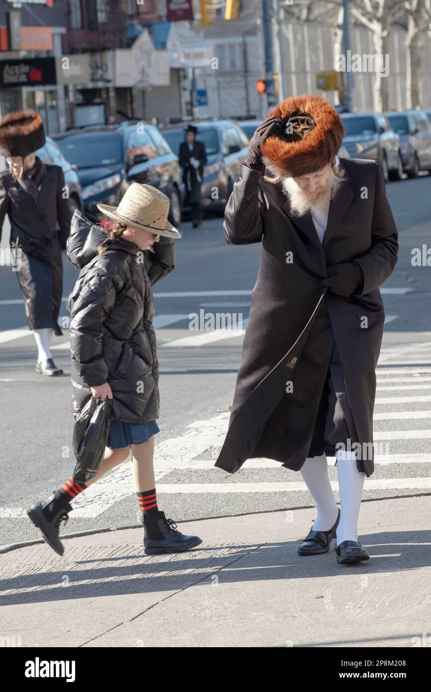A street scene of people crossing the streets in Williamsburg, Brooklyn, New York. The  men are orthodox Jews the girl is not. 2023. Stock Photo
