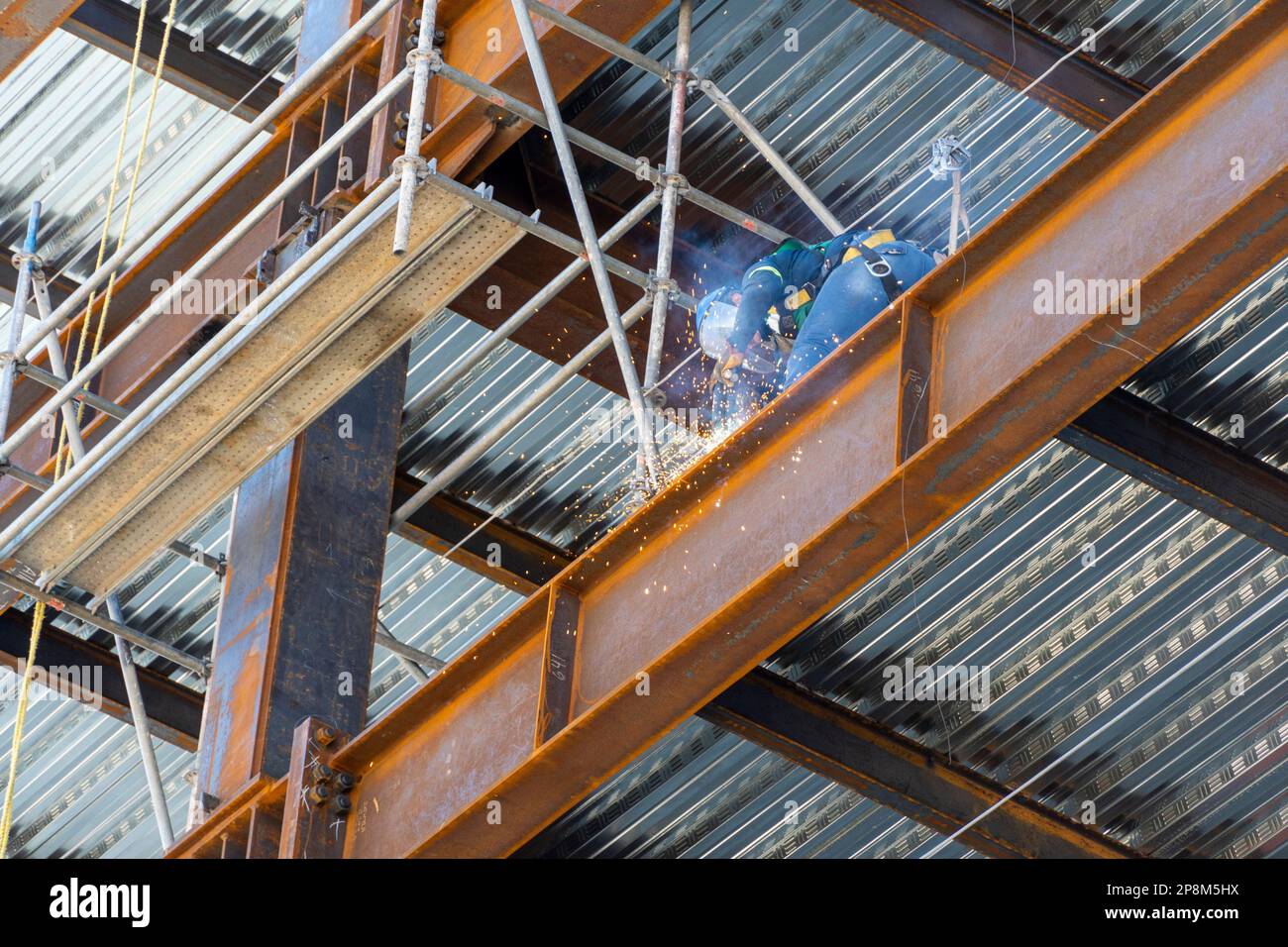 A construction worker using an angle grinder on a scaffold Stock Photo