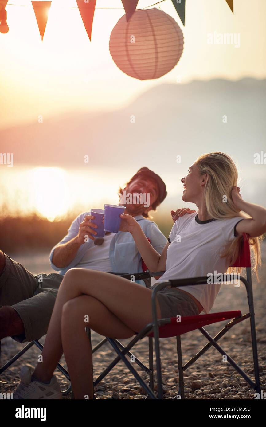 couple laughing at sunset, looking each other, toasting, enjoying Stock Photo