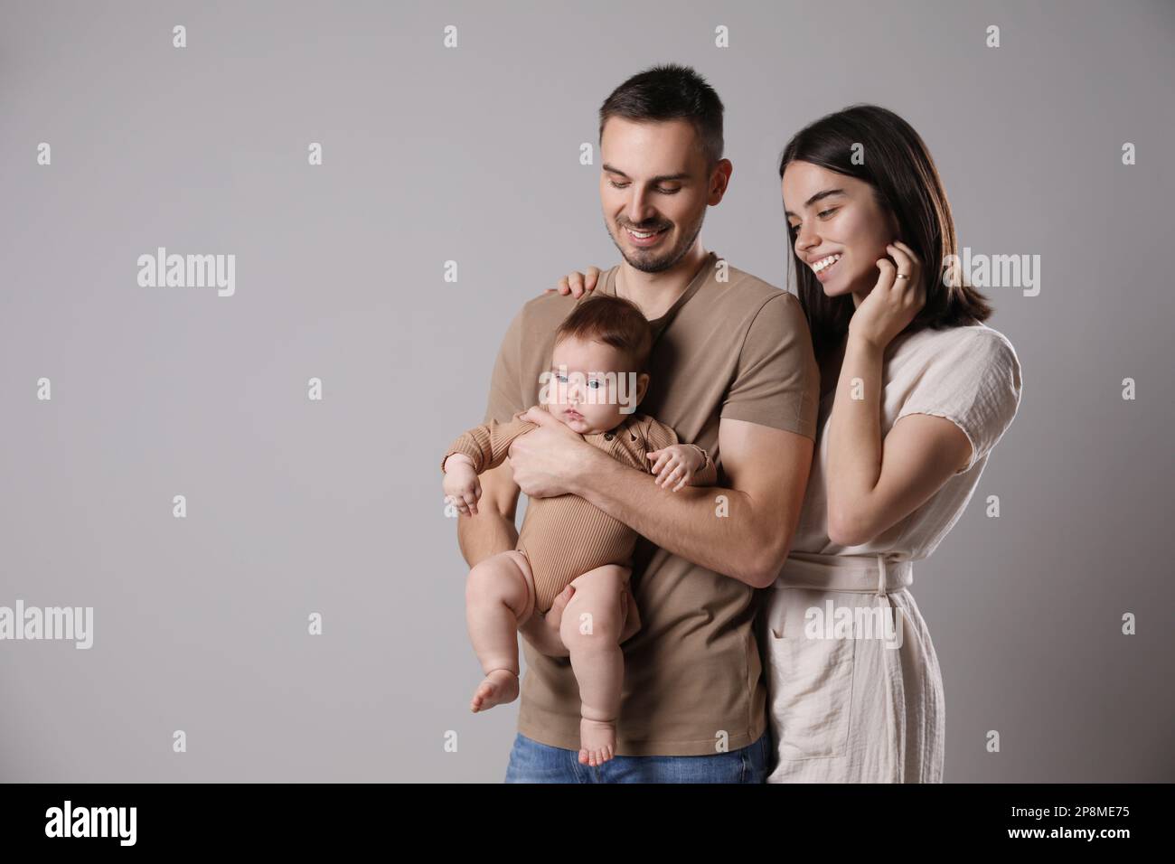 Happy family. Couple with their cute baby on grey background ...