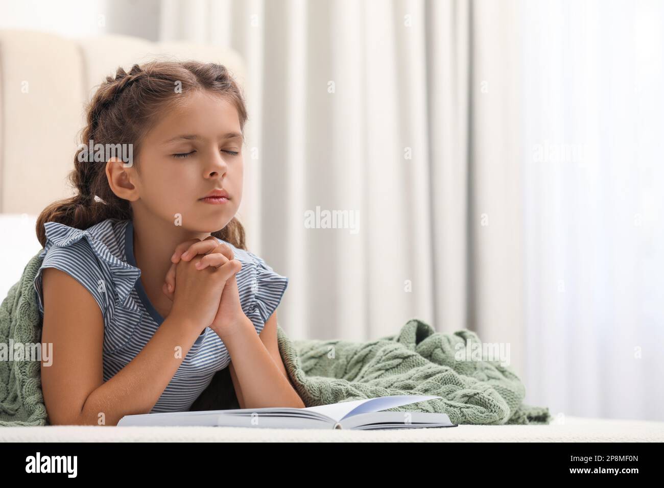 Cute little girl praying over Bible in bedroom Stock Photo Alamy