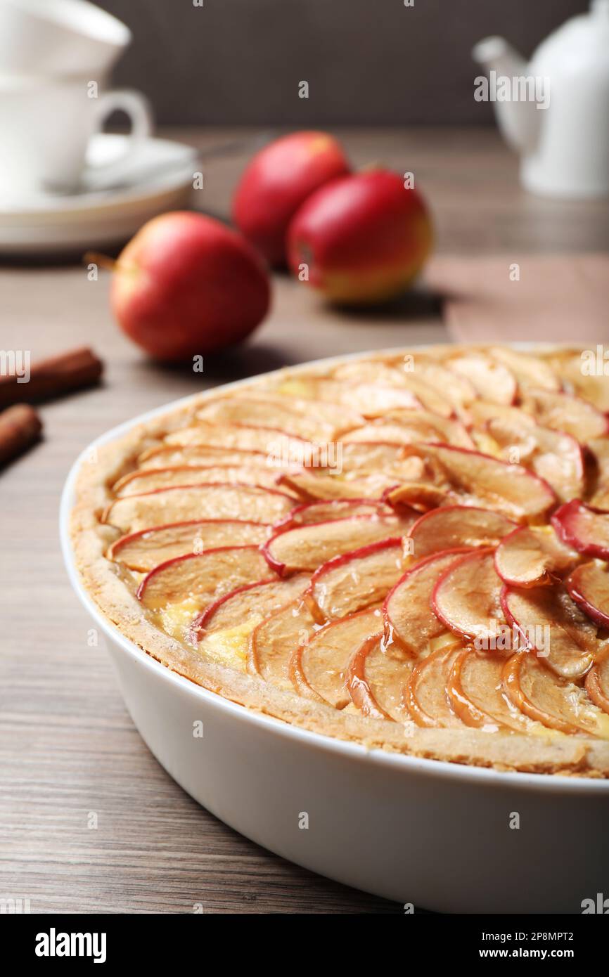 Tasty apple pie in baking dish on wooden table, closeup Stock Photo