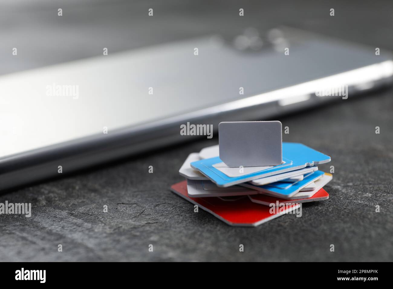 SIM cards and mobile phone on grey table, closeup Stock Photo