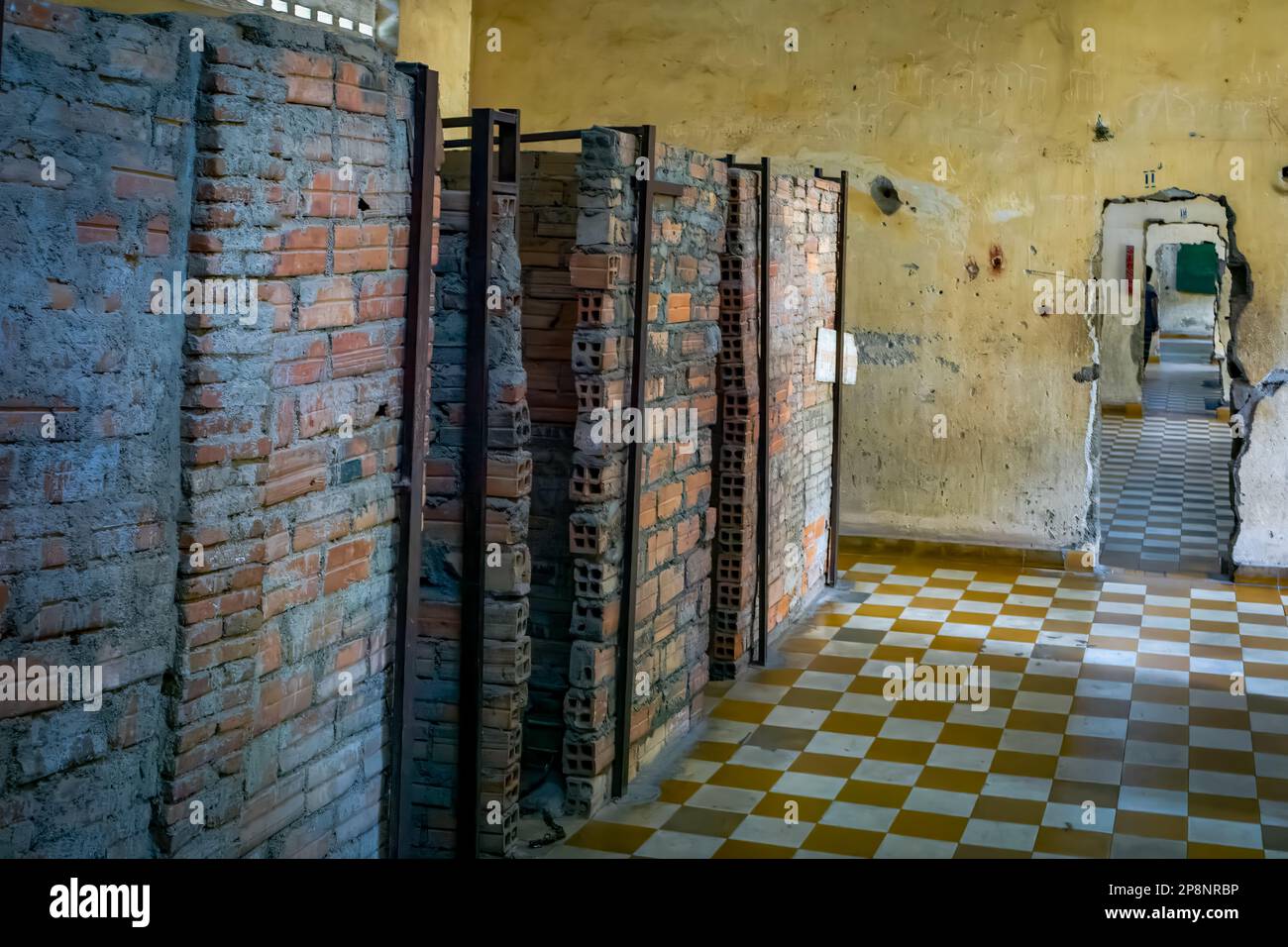 Rough built cells and doorways punched through concrete walls linking former former classrooms in the notorious Tuol Sleng S-21 torture and genocide Stock Photo