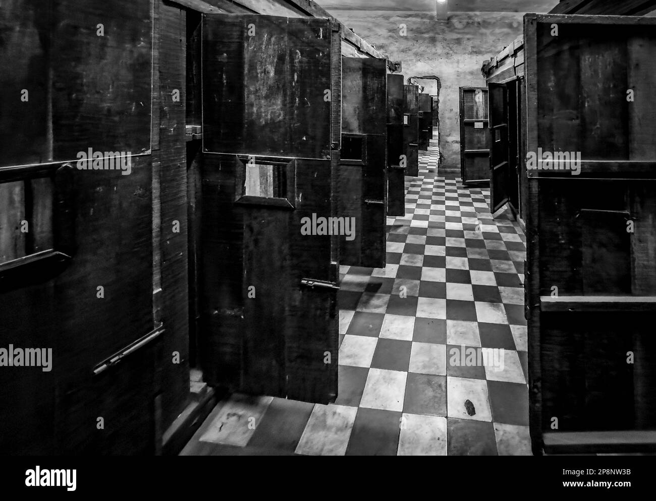 Rough wooden cells and doorways punched through concrete walls linking former former classrooms in the notorious Tuol Sleng S-21 torture and genocide Stock Photo