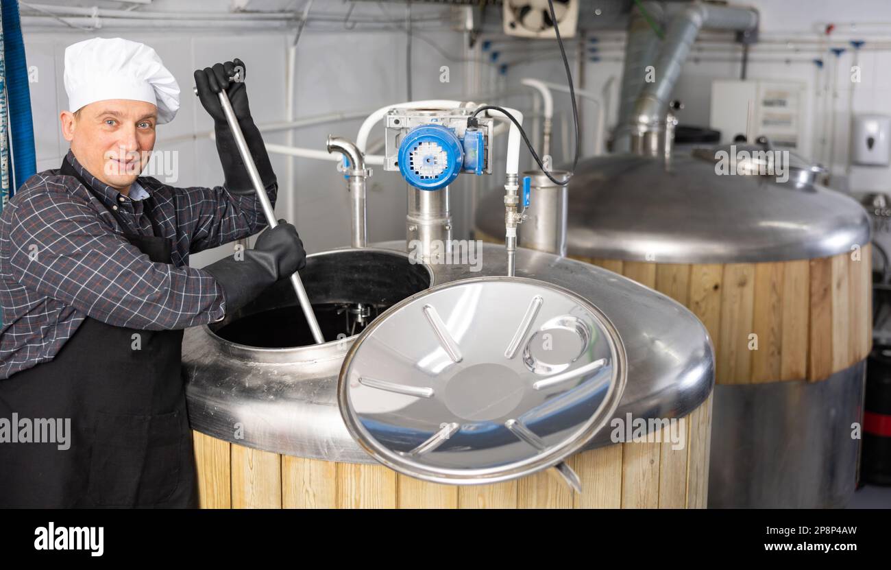 Beer factory worker mixing beer in tank Stock Photo Alamy