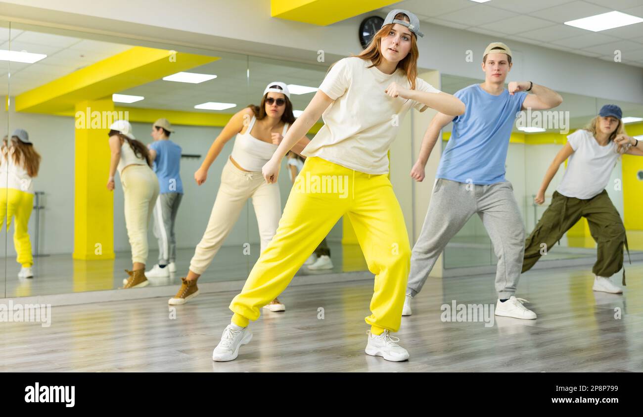 Group of young teen boy and girls dancing in spacious hall with mirrors