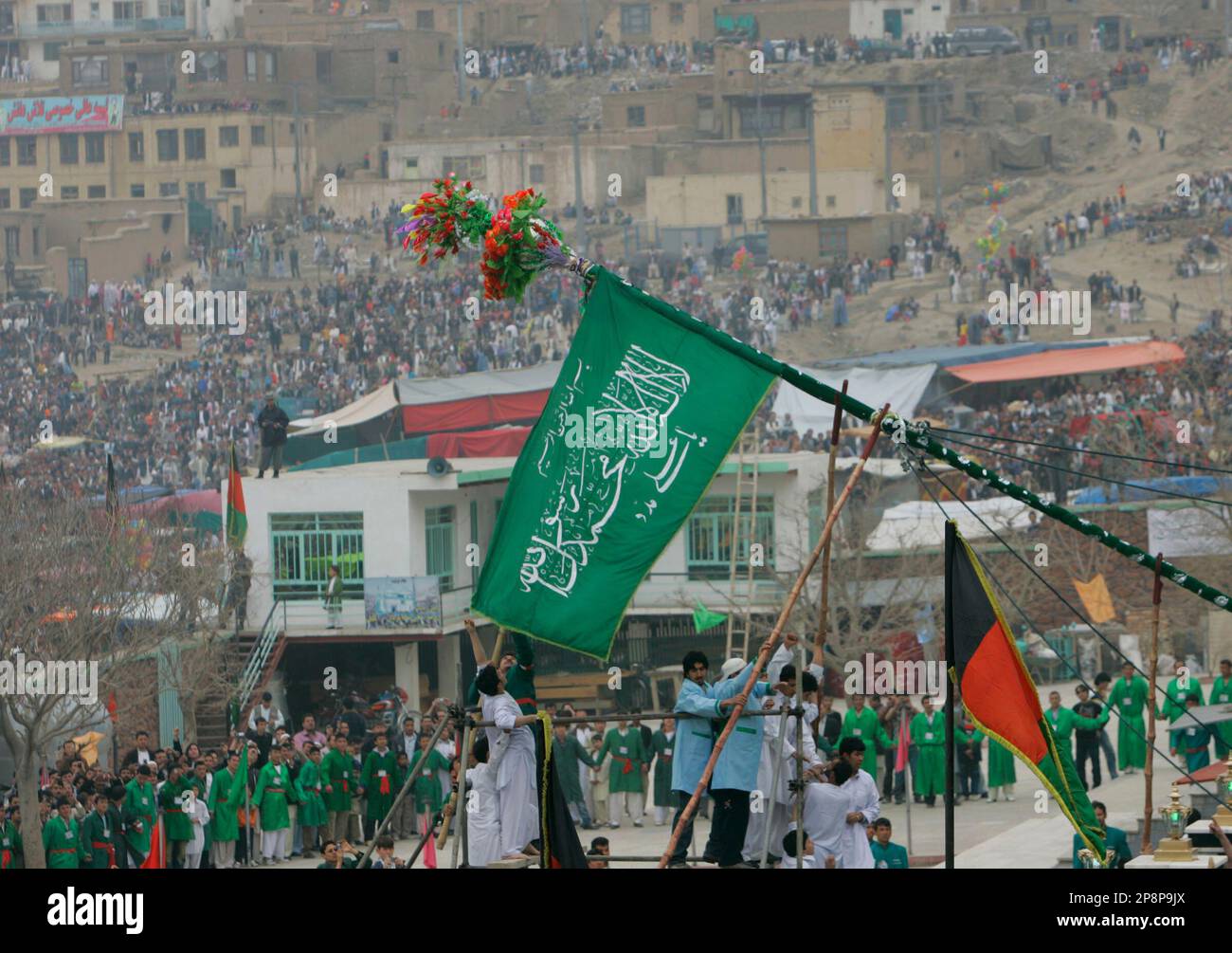 Afghan men raise the holy mace during a celebration of the Persian New