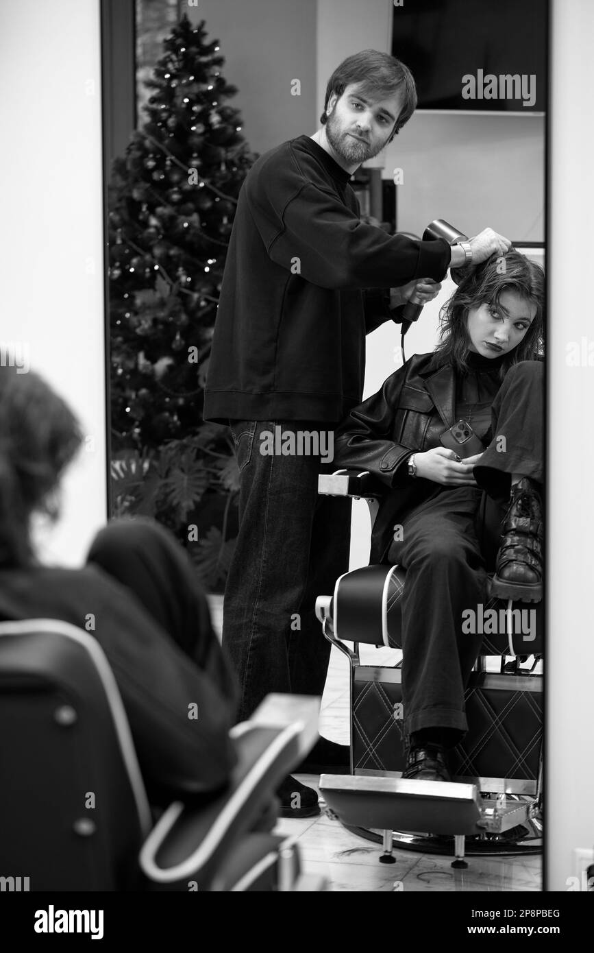Beautiful young woman in modern hair salon. hairdresser checking