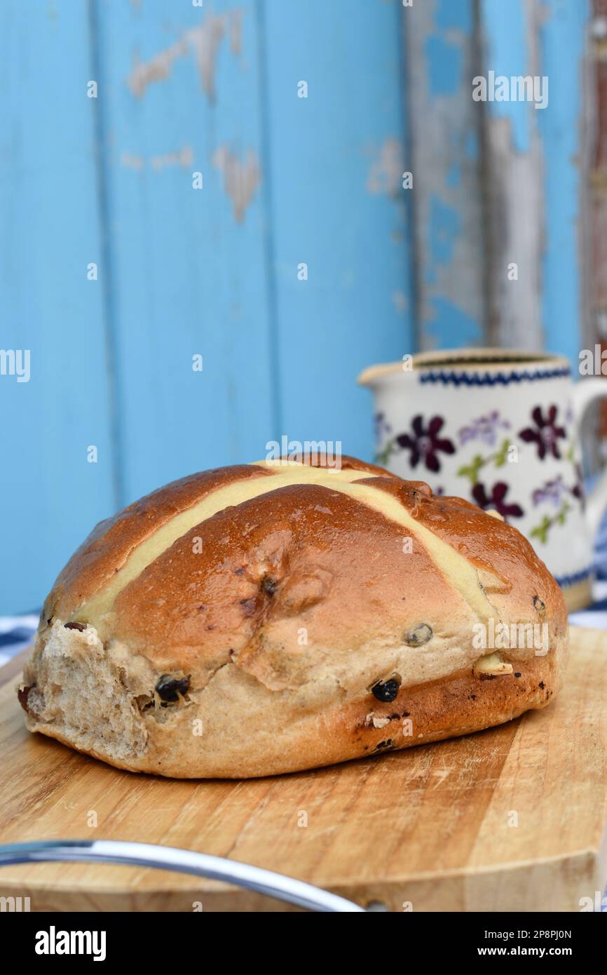 Giant hot cross bun on a chopping board. Traditional spiced, sticky
