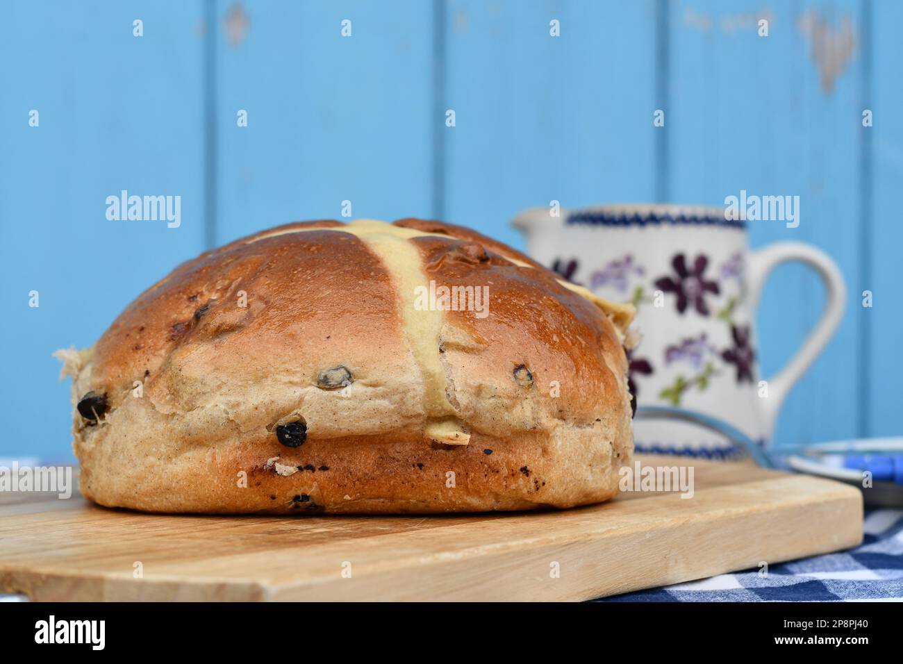 Giant hot cross bun on a chopping board. Traditional spiced, sticky