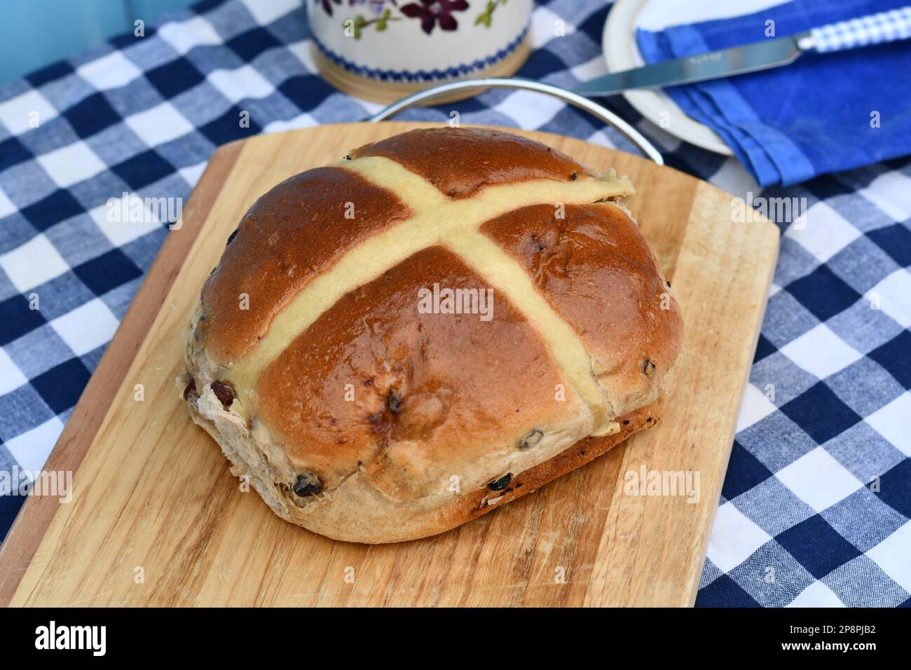 Giant hot cross bun on a chopping board. Traditional spiced, sticky