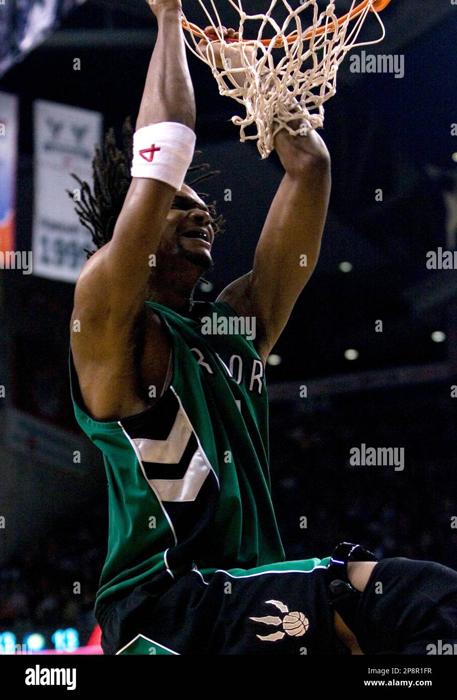 Toronto Raptors' Chris Bosh, wearing a green jersey for St. Patrick's Day,  hangs from the hoop after scoring against Indiana Pacers during  second-quarter NBA basketball game action in Toronto on Sunday, March